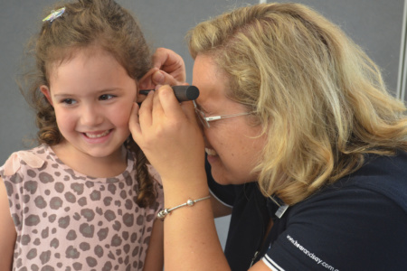 Women Looking In Girls Ear For Hearing Test