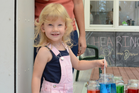 Girl With Jars Of Coloured Water Smiling At Camera