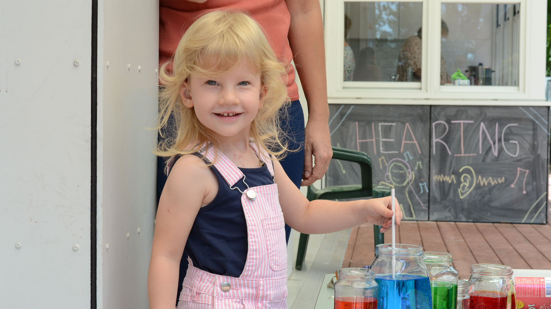 Girl With Jars Of Coloured Water Smiling At Camera