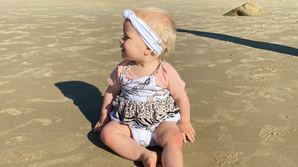 Baby With Cochlear Implants Sitting On Beach