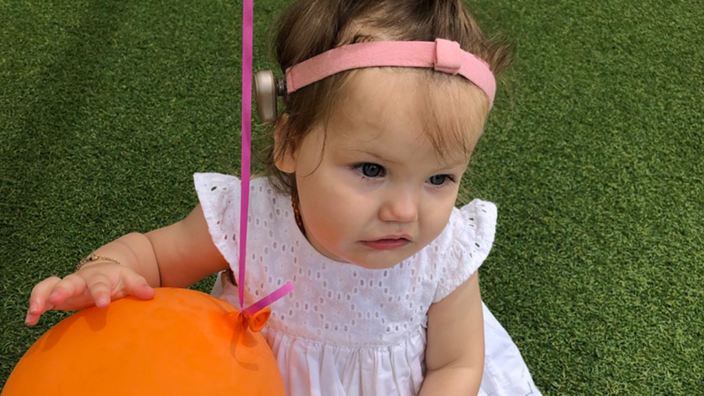 Violet Wearing Bone Anchored Hearing Aid Holding Orange Balloon