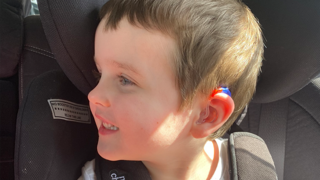 Img Sam Wearing His Blue And Red Hearing Aid